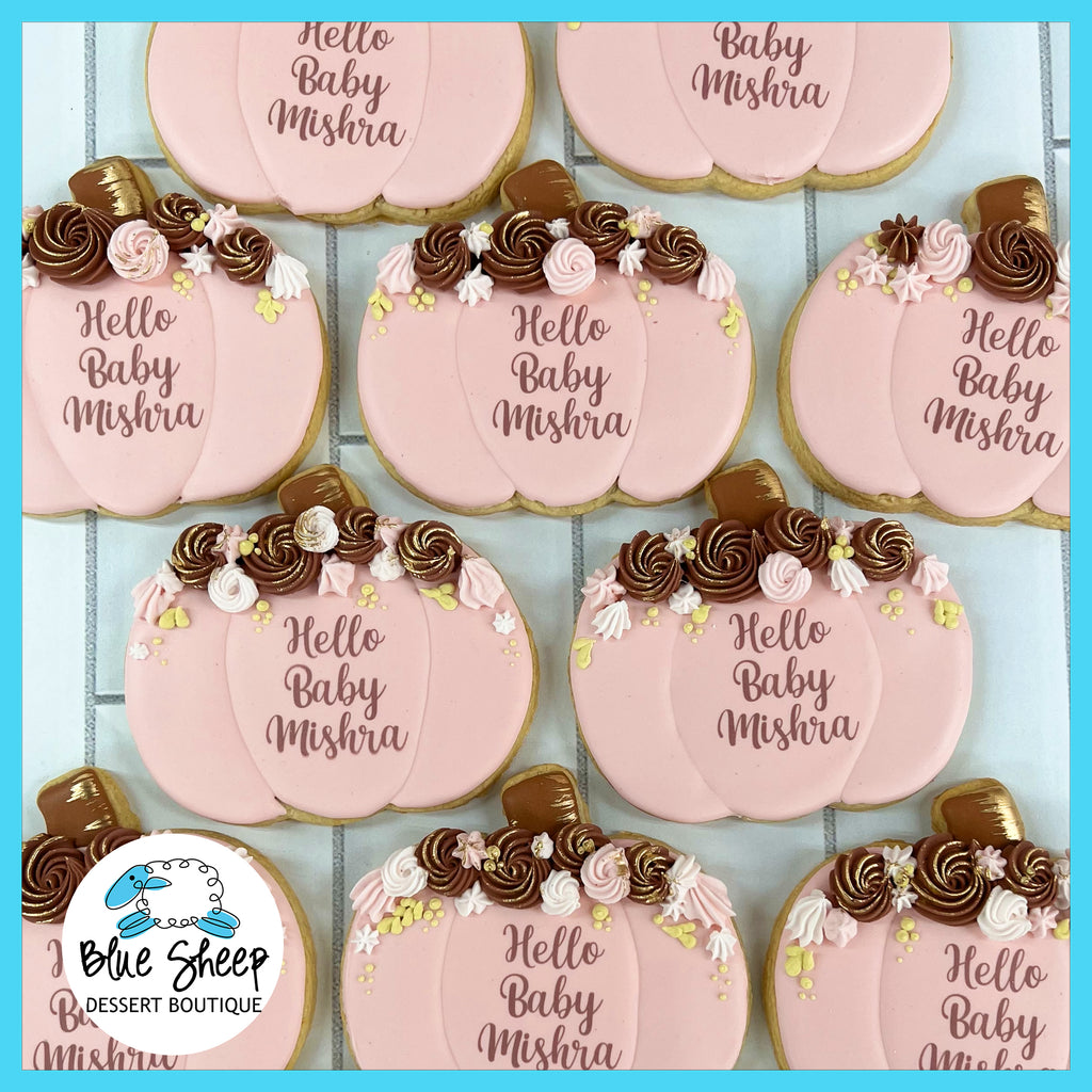 NJ customized pumpkin-shaped decorated sugar cookie favors, in blush pink and burgundy colors, for a baby shower. These read "Hello Baby Mishra"